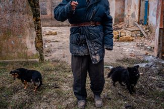 Мужчина выгуливает собак возле разрушенного Дома культуры в Александровке