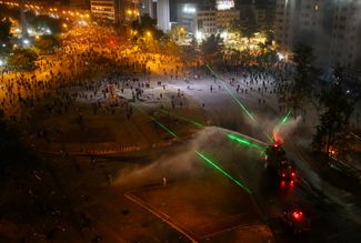 Участники антиправительственных митингов в столице Чили городе Сантьяго используют лазеры против спецназа. 1 ноября 2019 года