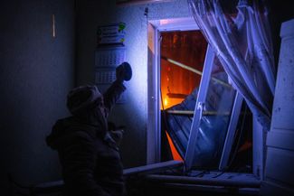 Жительница Донецка осматривает свой дом после обстрела