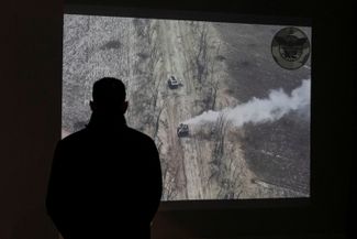 Мужчина на выставке смотрит видео, как российский танк атакуют с беспилотника. Киев, 9 мая 2022
