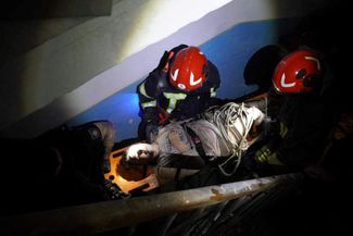 Спасатели выносят пострадавшую в результате ракетного удара во Львове