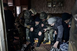 Police officers help an elderly resident of Avdiivka to leave the house and get to the car in which he is being evacuated from the combat zone