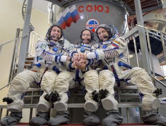 Шейн Кимброу, Сергей Рыжиков и Андрей Борисенко позируют на фоне тренажера «Союз» в Звездном городке. 31 декабря 2016 года
