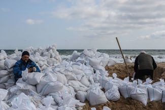Добровольцы наполняют мешки с песком на пляже в Одессе. Их будут использовать для создания укреплений в городе.