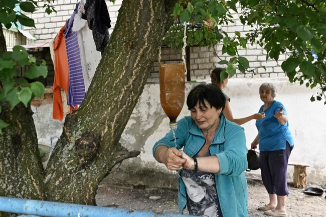 Женщина из Северска моет руки возле подвала жилого дома, где люди укрываются от обстрелов