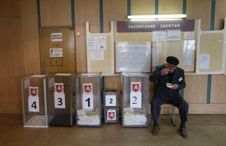 Член избирательной комиссии рядом с избирательными урнами во время референдума о статусе Крыма, Симферополь, 16 марта 2014 года