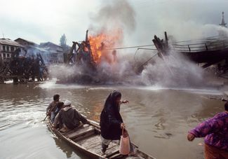 Жители города Шринагар Кашмирской долины переплывают реку Джелам, мост через которую подожгли сепаратисты. 1 сентября 1990 года