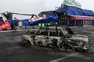 Сгоревший автомобиль после обстрела торгового центра в Горловке