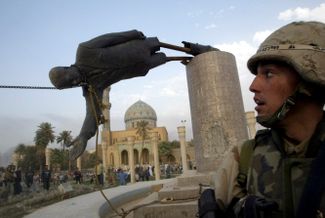 9 апреля 2003 года. Багдад. Столицу взяли без боя. Свержение статуи Хусейна, ставшее символом смены власти в стране, показали в этот день телеканалы по всему миру. Сбивать статую, стоящую на площади недалеко от отеля, где жили журналисты со всего мира, начала группа иракцев, однако сбросили монумент в итоге американские военные, пригнавшие тягач. Эта статуя была не главным в Багдаде монументом Хусейна, зато стояла недалеко от отеля, где жили иностранные журналисты, что и превратило ее снос в символ этой фазы операции. Питер Маас, который работал в апреле 2003 года в Багдаде, подробно реконструировал события этого дня <a href="https://www.newyorker.com/magazine/2011/01/10/the-toppling" target="_blank">в статье</a>, которая вышла в The New Yorker в 2011 году.