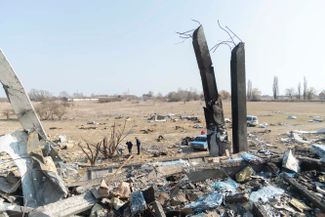 Двое мирных жителей осматривают руины, оставшиеся после взрыва завода пищевой промышленности в Броварах, Киевская область