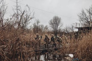 Бойцы ВСУ переходят ручеек по поврежденному мостику
