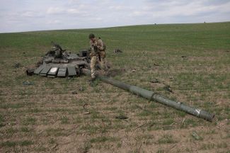 Украинский военный рядом с оторванной взрывом башней российского танка.<br>