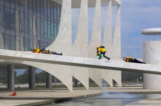 Участники штурма президентского дворца в Бразилиа укрываются от полиции, применившей слезоточивый газ