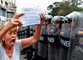 Женщина протестует и показывает полицейским плакат «Друг, хватит защищать коррумпированное правительство, вспомни про конституцию!». 4 мая 2019 года