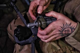 Украинский военнослужащий прикрепляет гранату к дрону