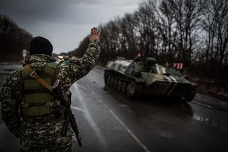Солдат на блокпосту приветствует украинских военных, которые едут в Дебальцево
