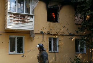Пожарный осматривает последствия обстрела жилого дома в Донецке