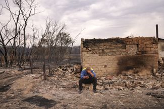 A man sits next to the ruins of his home, which was destroyed by wildfires in the Auliekol district. Kostanay region, September 2022.