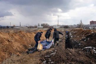 Mariupol residents bury a body in a mass grave. March 9, 2022.