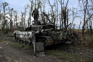 Украинский военный обследует оставленный после отступлений российский танк