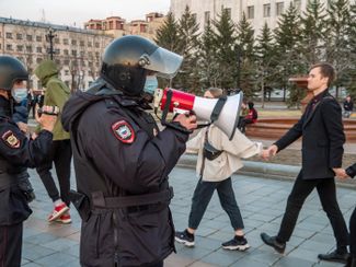 Protesters dancing in a circle on Lenin Square in Khabarovsk. Meanwhile, a police officer with a megaphone demands that they clear the area.
