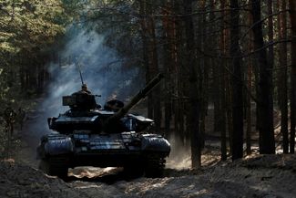 Украинские военные едут на захваченном российском танке недалеко от Купянска