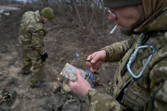 Боец ВСУ вскрывает телефон погибшего российского военного рядом с Куриловкой