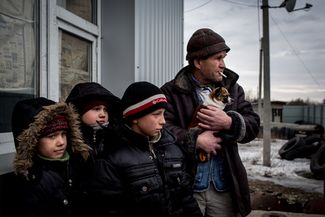 A group of children and a man await to be evacuated from a pickup point in the disputed town. 31 January 2015.