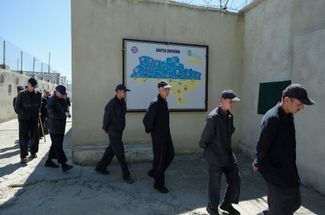 Российские военнопленные идут мимо карты Украины во дворе следственного изолятора в неизвестном месте во Львовской области