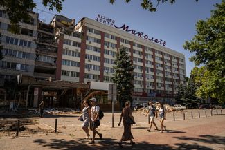 Жители города идут мимо гостиницы «Николаев», разрушенной в результате российского удара в середине июля