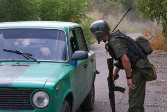 Военнослужащий Народной милиции самопровозглашенной ДНР проверяет проезжающую блокпост машину