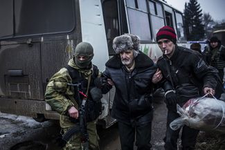 An elderly Ukrainian man is helped by a Ukrainian Army soldier and a citizen during a evacuation of civilians, February 3, 2015.