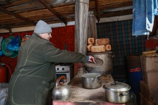 Жительница поселка Валентина готовит еду на плите в своем доме