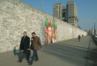 Pedestrians walk along a wall in Kaliningrad. March 2004.