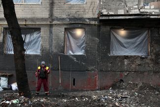 Муниципальный работник возле жилого дома, поврежденного обломками ракет
