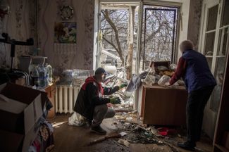 Residents of a house destroyed by a rocket attack tidy up their apartment