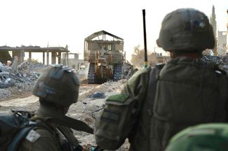 Военнослужащие ЦАХАЛ в ходе наземной операции в секторе Газа. На фото видно, как перед колонной бронетехники двигаются бронированные бульдозеры — для разминирования маршрута, по которому израильские военные углубляются внутрь территории сектора