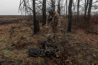 Боец ВСУ осматривает тело российского солдата