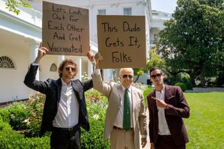 Джо Байден фотографируется с инфлюенсером Сетом Филлипсом для его инстаграма @dudewithsign. Надписи на плакатах: у Филлипса — «Давайте заботиться друг о друге и привьемся», у Байдена — «Этот чувак догоняет, ребята». Белый дом, Вашингтон, 6 августа 2021 года