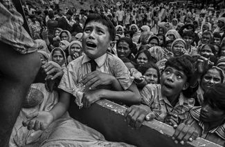 Категория «Новостная фотография», второе место в номинации «Фотоистория». Беженец забирается на грузовик, в котором привезли гуманитарную помощь, в лагере для беженцев рохинджа в Бангладеше, 20 сентября 2017 года