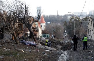 Полицейские осматривают одно из зданий, пострадавших при обстреле Киева