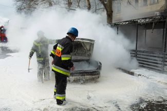 Украинские пожарные тушат машину, загоревшуюся в ходе артиллерийского обстрела Николаева российскими войсками