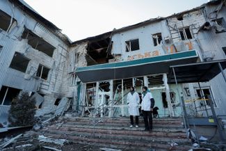 Медицинские работники рядом с разрушенной больницей в Волновахе. 12 марта 2022 года