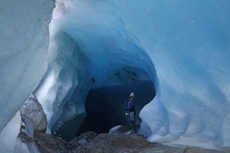 Гляциолог Австрийской академии наук стоит в ледяном туннеле, образованном потоком талой воды внутри ледника Гепатшфернер в Альпах
