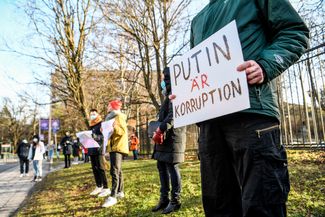 Протестующий с плакатом «Путин — это коррупция» в Стокгольме