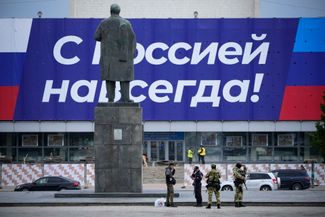 Российские военнослужащие, патрулирующие улицу, остановились у памятника Владимиру Ленину 
