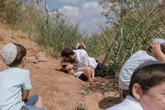 Мужчина прикрывает своим телом ребенка во время воздушной тревоги в израильском городе Реховот. 13 октября 2023 года