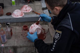 Старший следователь по особо важным делам администрации Харьковской области ищет отпечатки пальцев на предметах, найденных в здании, которое российские военные использовали как штаб