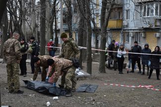 Полиция осматривает тело местного жителя, погибшего в результате попадания российской ракеты в жилой дом