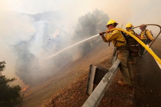 Пожарные защищают от огня железнодорожный мост возле калифорнийского города Куинси, 5 августа 2021 года